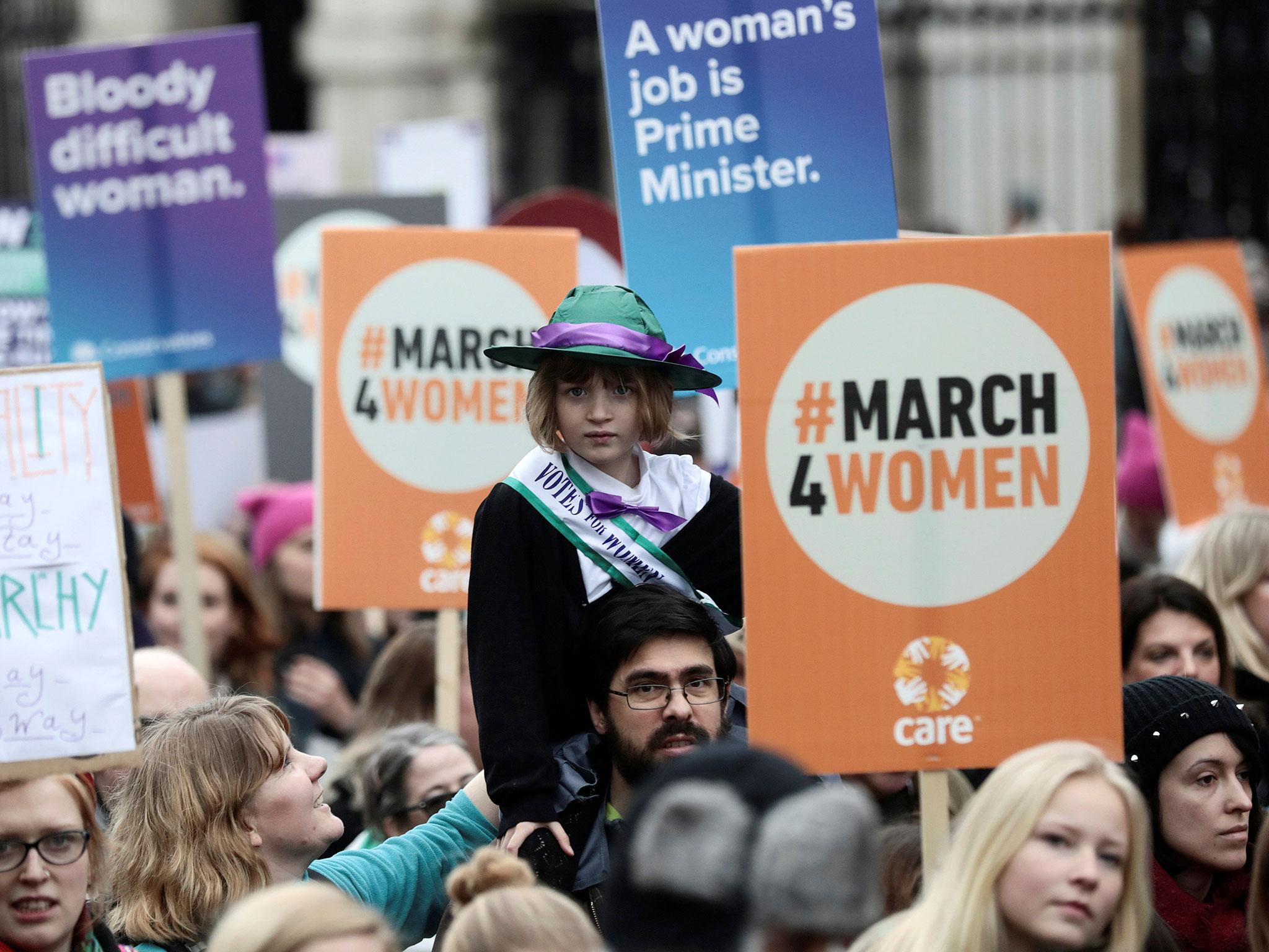 A young girl dressed as a suffragette during the March4Women near signs reading ‘Bloody difficult woman’ and ‘A woman’s job is Prime Minister’ (Dominic LipinskiPA)