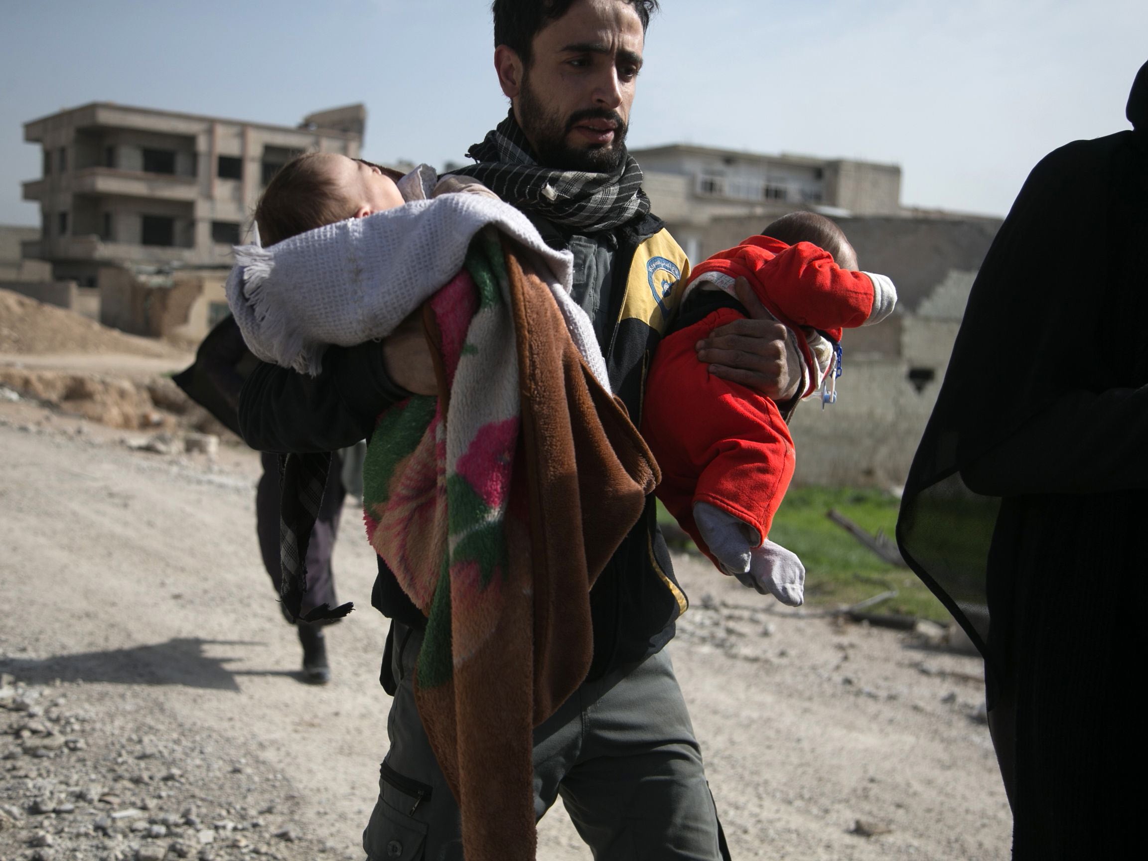 A Syrian civil defence volunteer carries children as he helps them try to flee their homes in the town of Hamouria in Syria’s besieged Eastern Ghouta