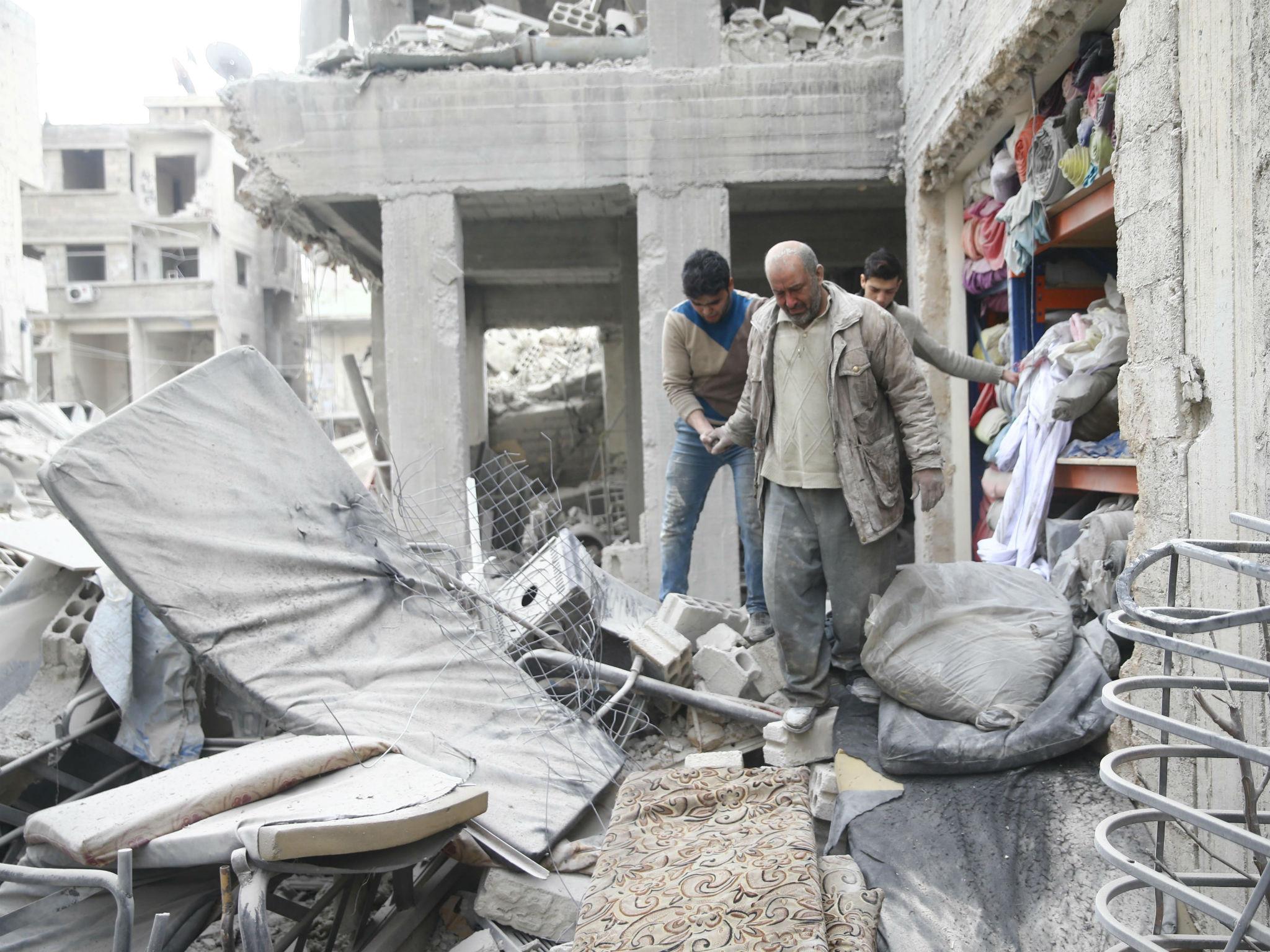 Abu Mohammad Alaya, 50, is helped after getting out from shelter in Douma, Syria