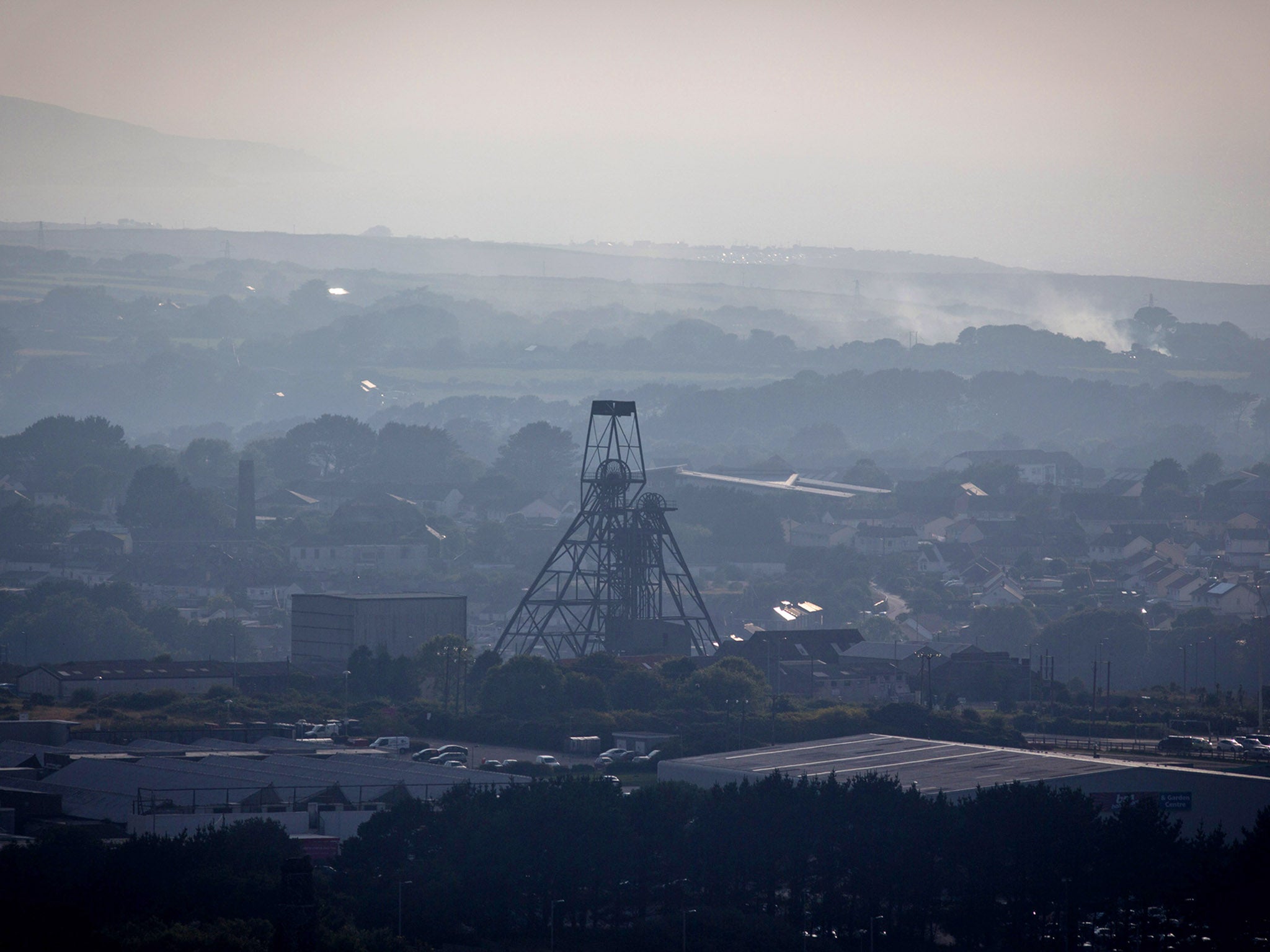 The disused mine shaft headgear and pulley wheel, seen over the town of Camborne