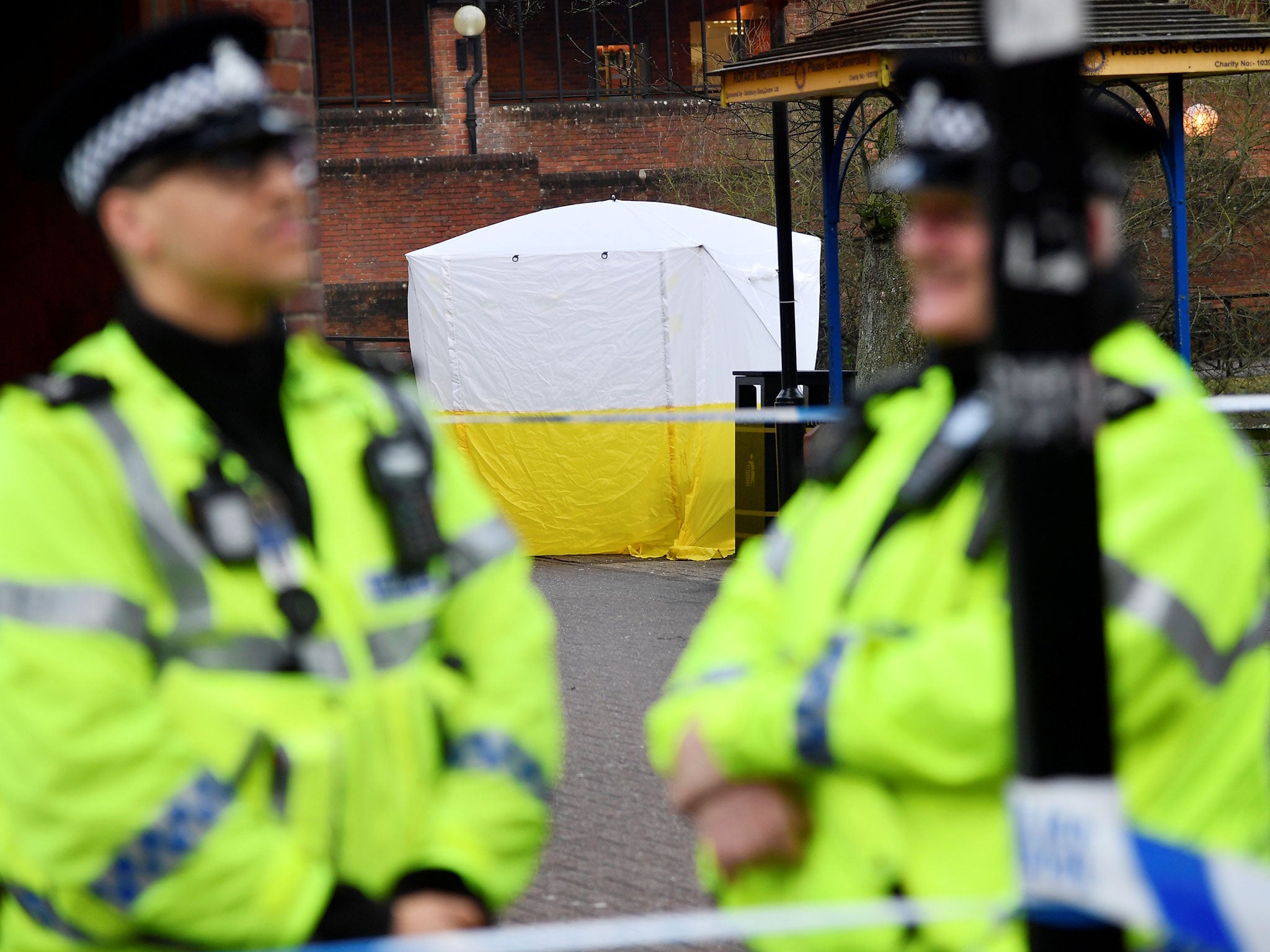 Police officers stand at crime scene tape, as a tent covers a park bench on which former Russian inteligence officer Sergei Skripal, and a woman were found unconscious after they had been exposed to an unknown substance, in Salisbury, Britain