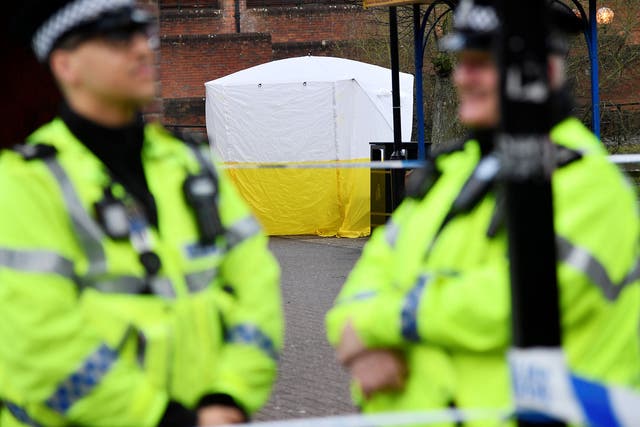Police officers stand at crime scene tape, as a tent covers a park bench on which former Russian inteligence officer Sergei Skripal, and a woman were found unconscious after they had been exposed to an unknown substance, in Salisbury, Britain