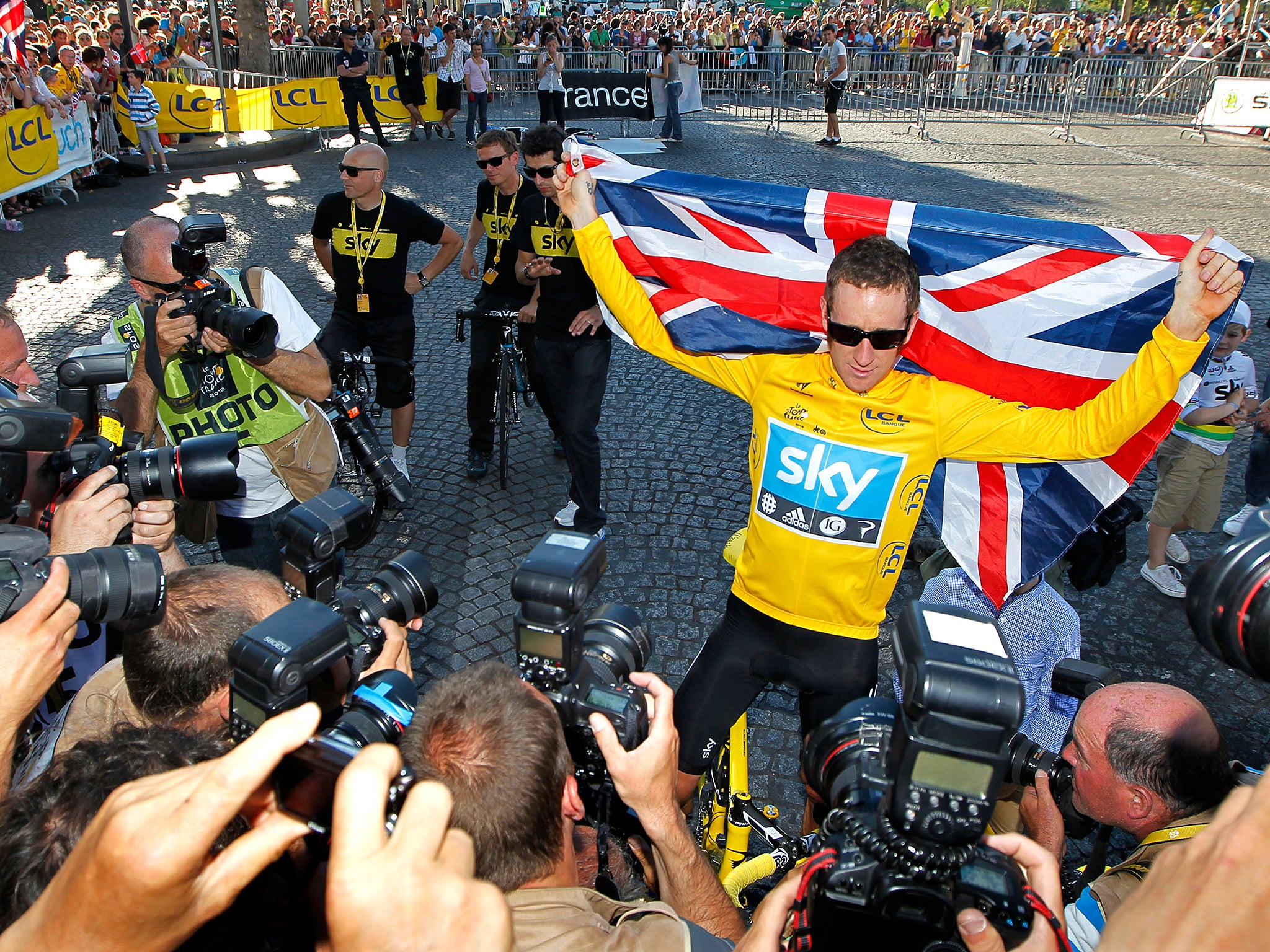 Wiggins surrounded by photographers celebrating his Tour de France victory on the Champs Elysees in 2012