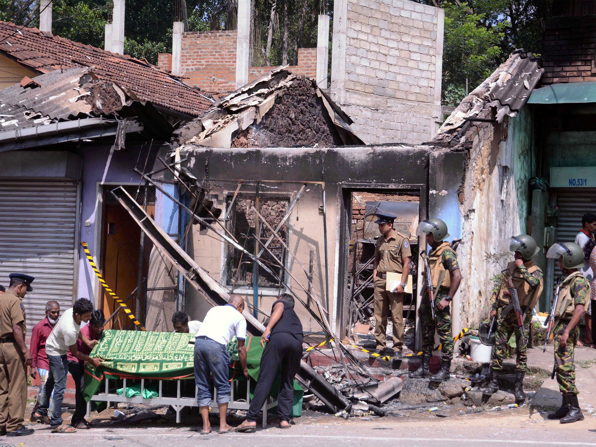 &#13;
Elite Sri Lankan forces and police officers stand guard near a house burnt down in the clashes in Digana, central Kandy &#13;