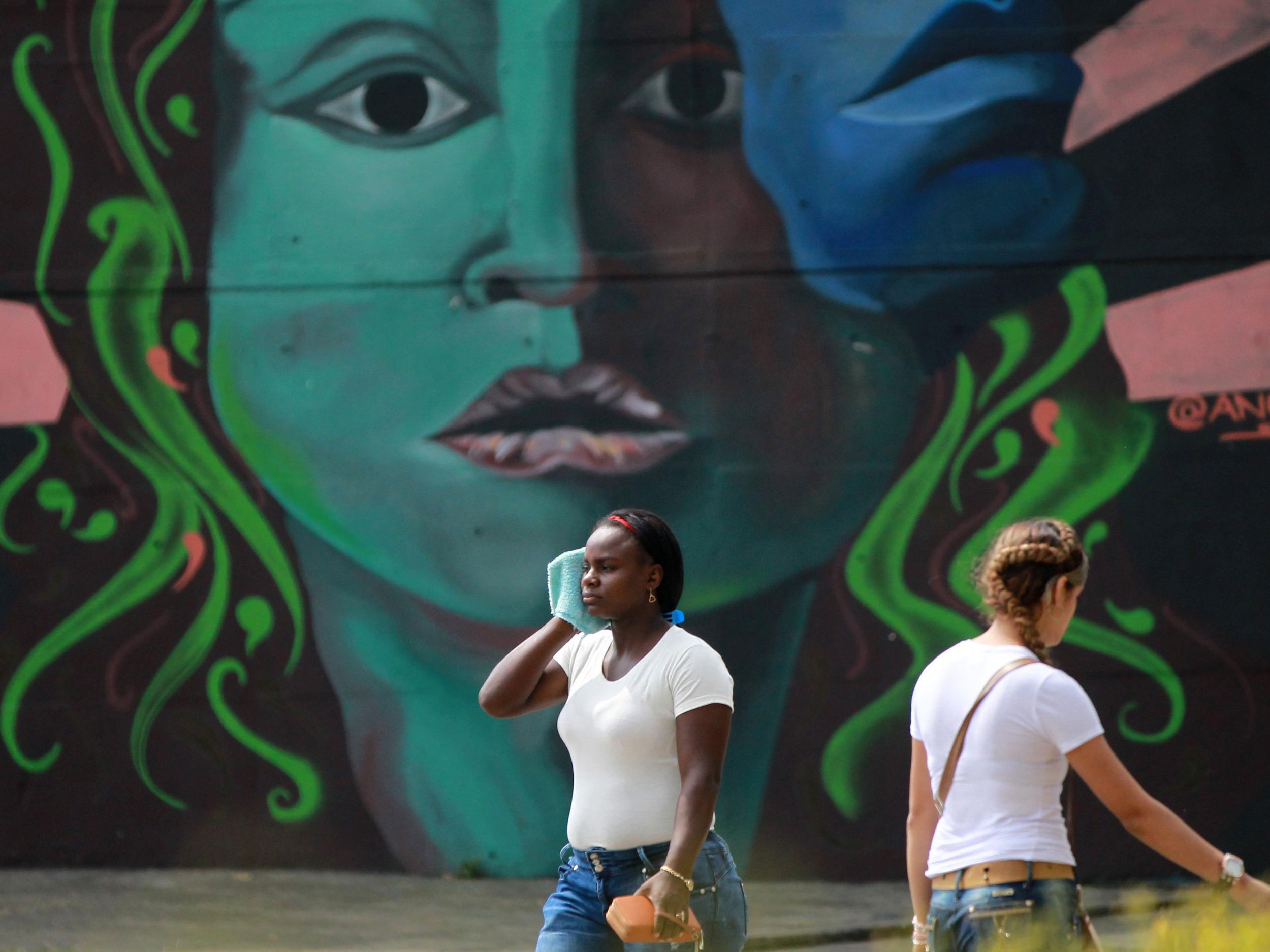 Women walk past a mural on the eve of the International Women's Day in Cali, Cauca Valley, Colombia, 7 March 2018
