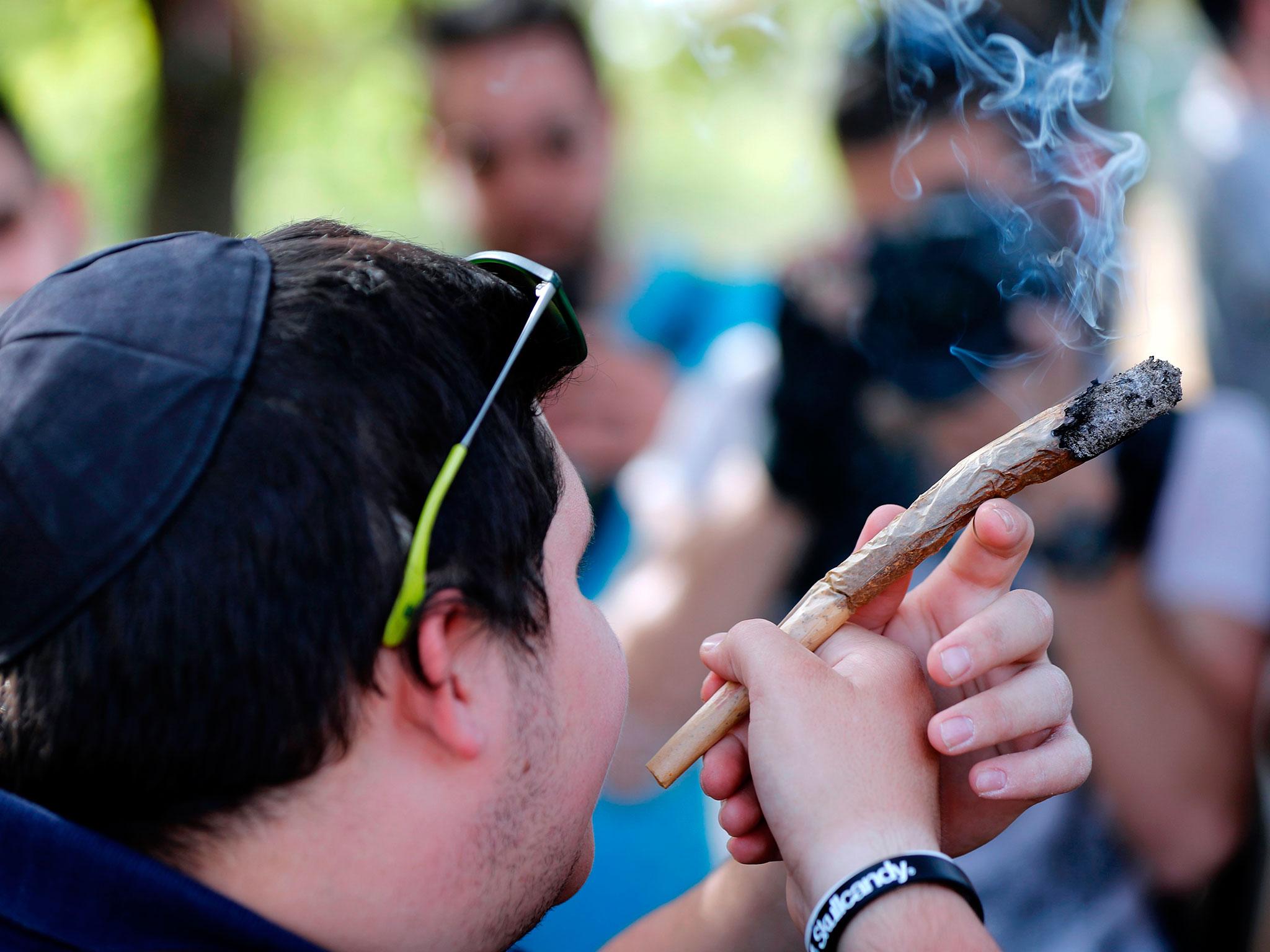 An Israeli man smokes a giant marijuana joint during a rally to celebrate '420' in the Rose garden, just across from the Knesset