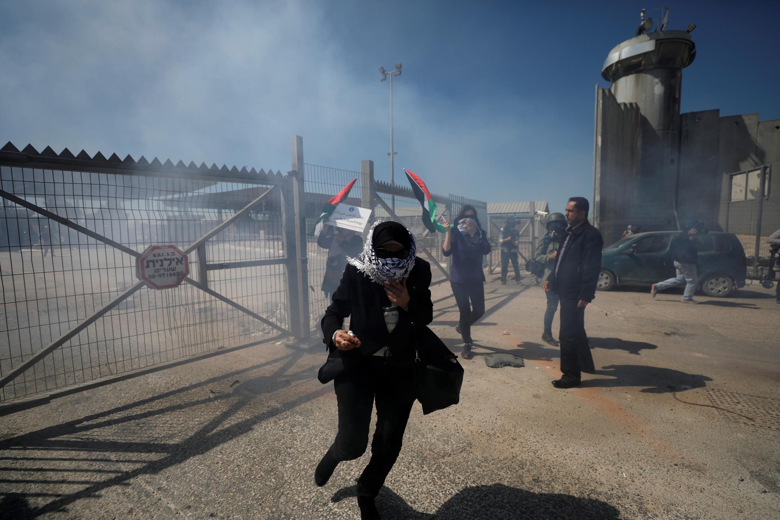 A Palestinian woman runs from tear gas fired by Israeli troops during clashes at a protest against US President Donald Trump's decision on Jerusalem in Ramallah in the occupied West Bank on 7 March 2018