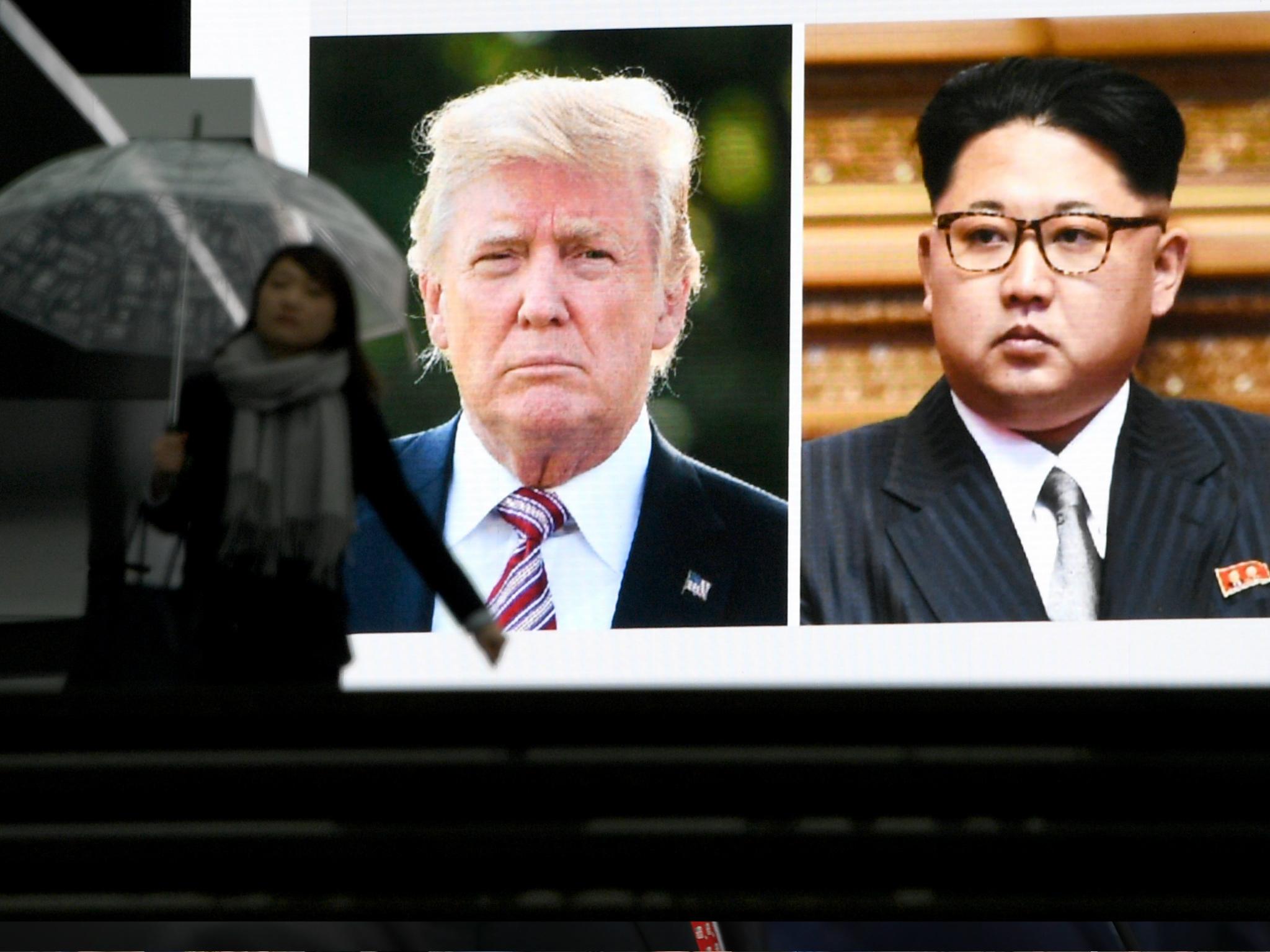 A pedestrian walks in front of a huge screen flashing a news report relating to US President Donald Trump and North Korean leader Kim Jong in Tokyo on 9 March 2018.