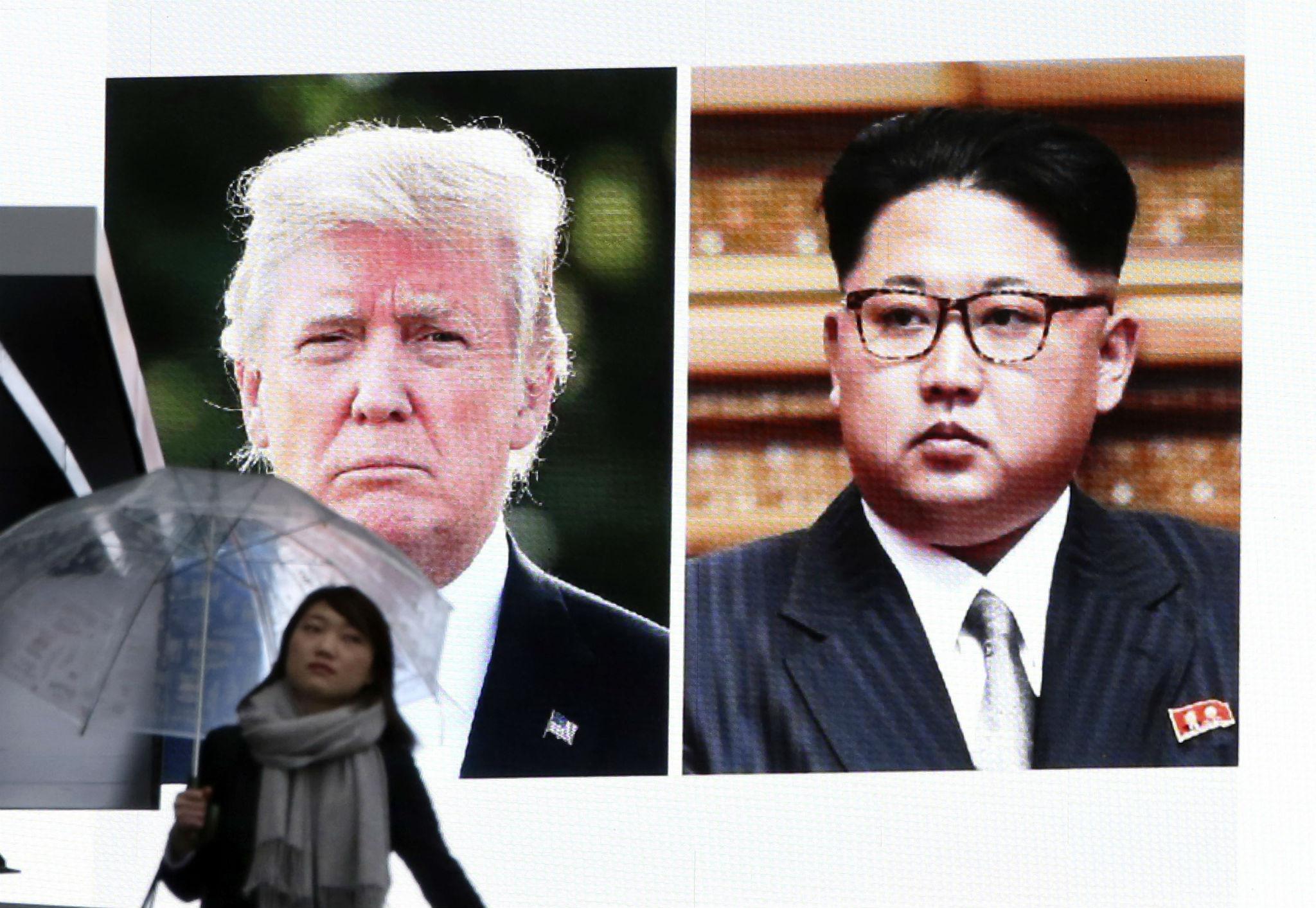 A woman walks by a huge screen showing U.S. President Donald Trump, left, and North Korea's leader Kim Jong Un, in Tokyo