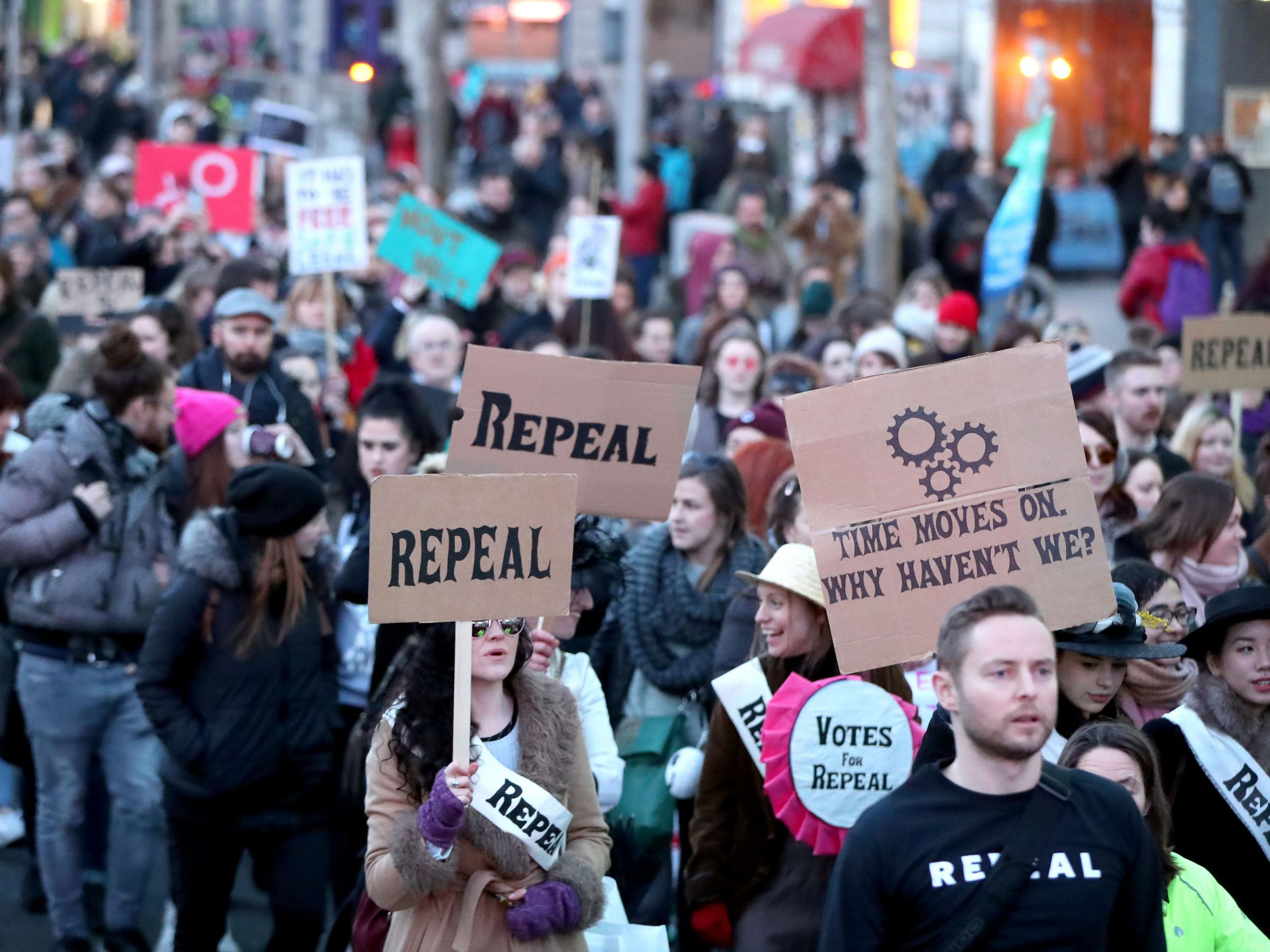 People carrying various signs, as participants take part in a march through Dublin city centre calling for the repeal of the eighth amendment to the Irish constitution
