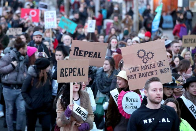 People carrying various signs, as participants take part in a march through Dublin city centre calling for the repeal of the eighth amendment to the Irish constitution