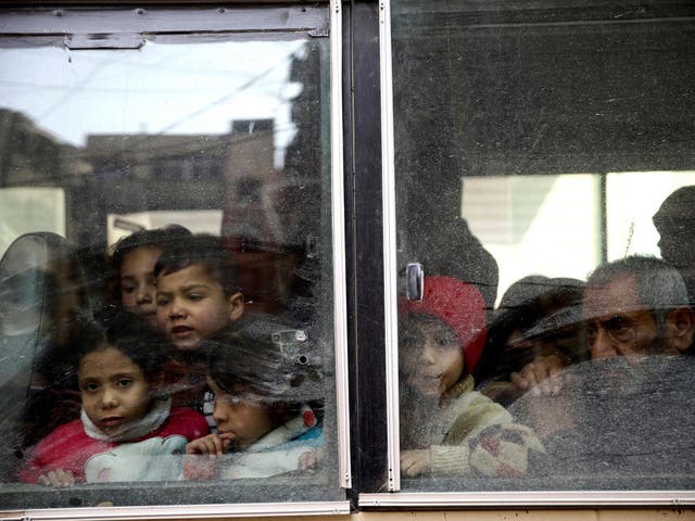 Children look through a bus window during evacuation from the besieged town of Douma, Eastern Ghouta, on Tuesday