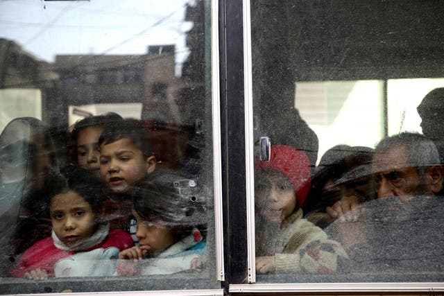 Children look through a bus window during evacuation from the besieged town of Douma, Eastern Ghouta, on Tuesday