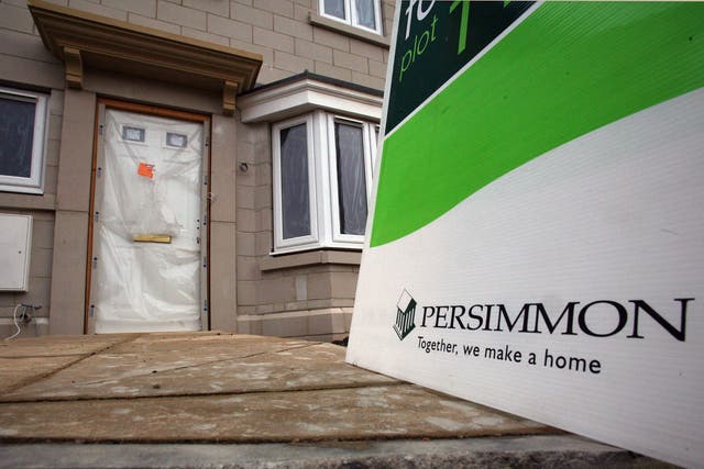A 'for sale' sign is displayed outside a new build house on a housing estate by developer and housebuilder Persimmon