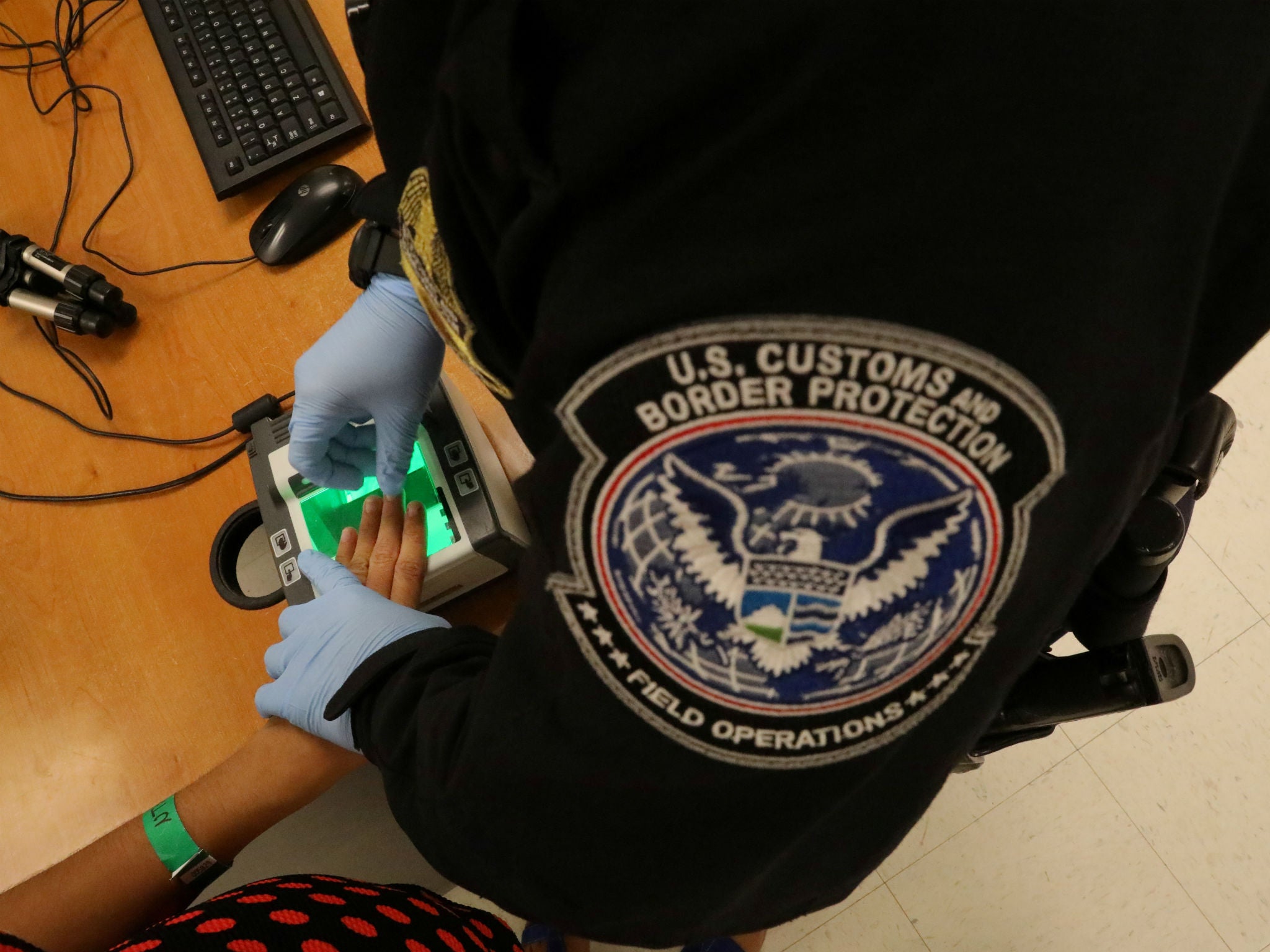 A woman who is seeking asylum has her fingerprints taken by a US Customs and Border patrol officer at a pedestrian port of entry from Mexico to the United States, in McAllen, Texas