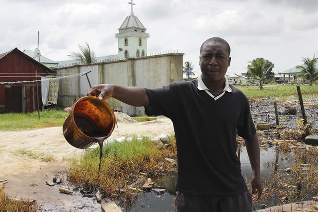 A villager shows a bucket of crude oil spill at the banks of a river, after a Shell pipeline leaked, in the Oloma community in Nigeria's delta region in 2014