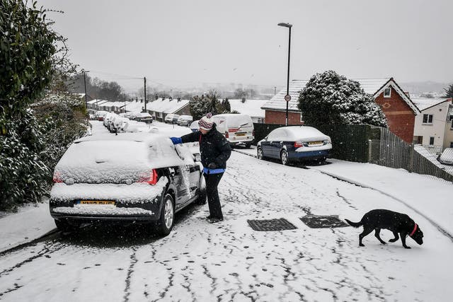 A woman clears snow off a car in Bristol after snow on Saturday