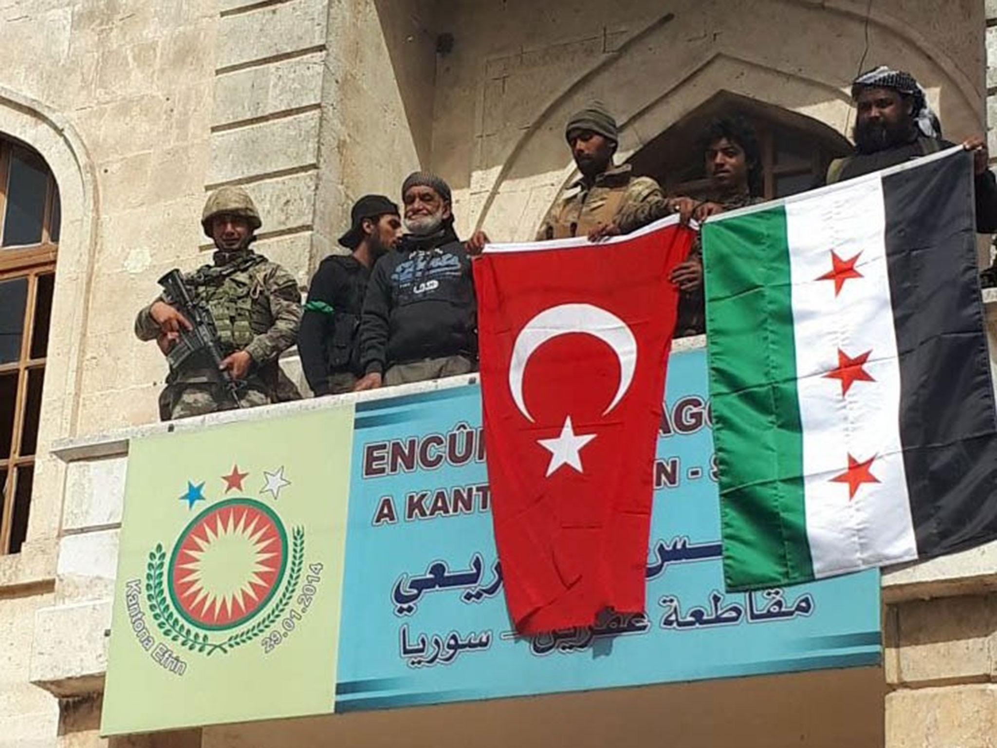 The army posted a video on social media showing a soldier holding a Turkish flag and a man waving the Syrian opposition flag on the balcony of the district parliament building (EPA/DHA/Dogan News Agency)