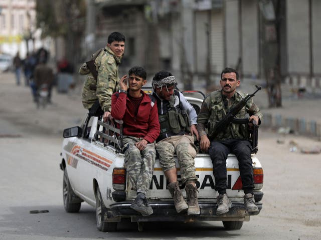 Turkish-backed Free Syrian army fighters ride on the back of a truck in Afrin on Monday