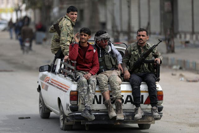 Turkish-backed Free Syrian army fighters ride on the back of a truck in Afrin on Monday