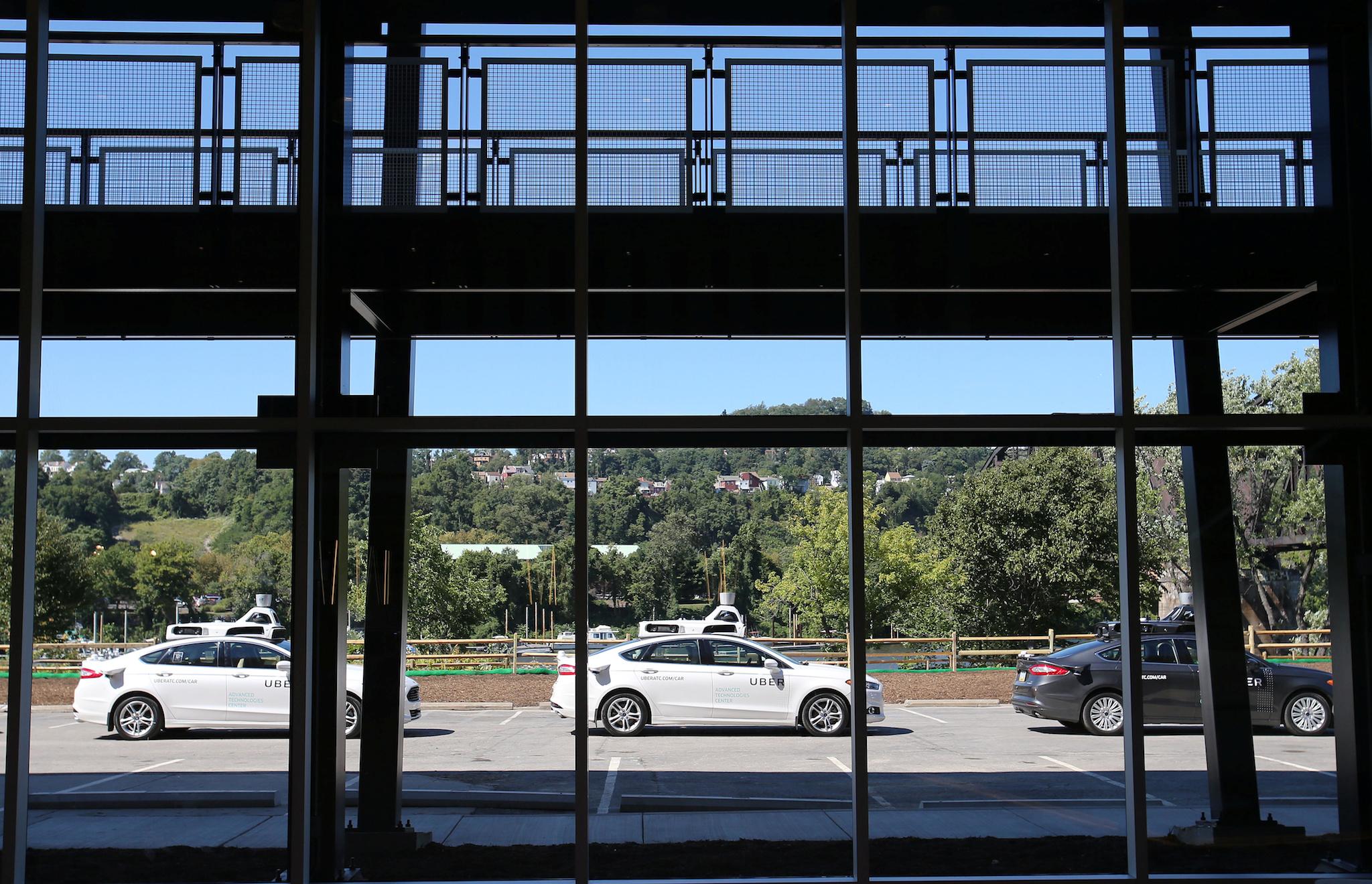 A fleet of Uber’s Ford Fusion self driving cars are shown through the lobby windows during a demonstration of self-driving automotive technology