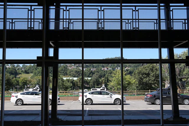 A fleet of Uber’s Ford Fusion self driving cars are shown through the lobby windows during a demonstration of self-driving automotive technology