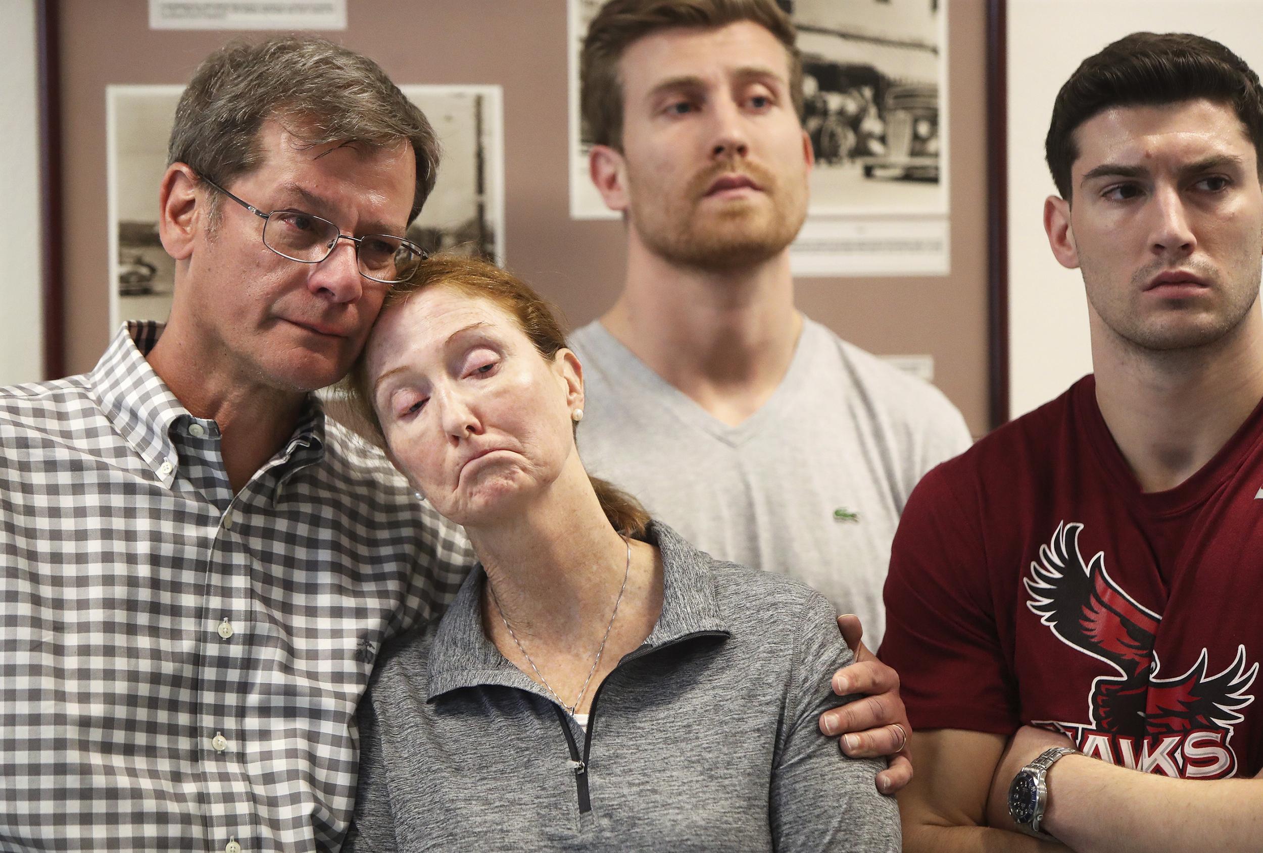 Parents John and Lisa Dombroski, left, stand with their sons John, behind, and Kevin during a press conference regarding their son and brother Mark