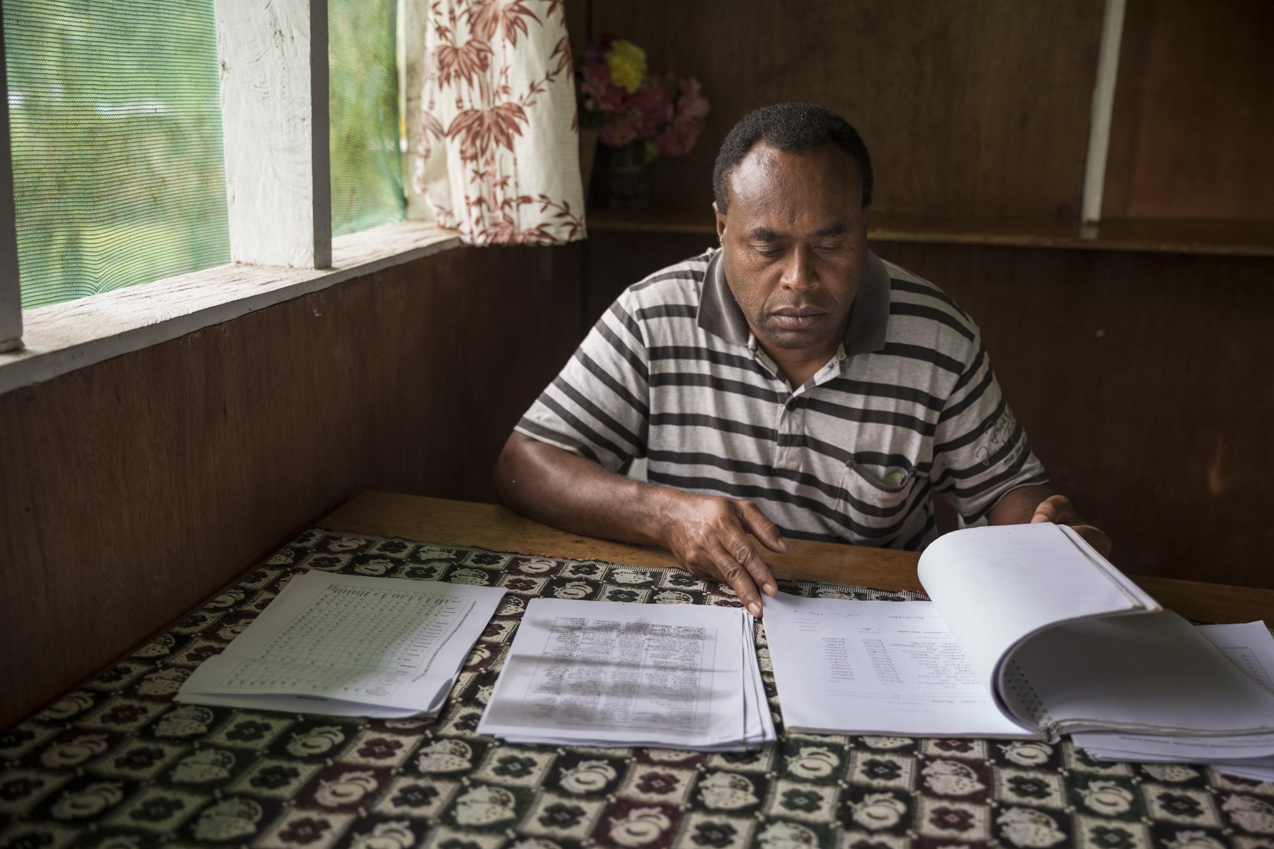 William Koiatuna, a community leader in the Pomio area, looks at petitions signed by local communities against proposed logging and oil palm plantation operations (Fabio Erdos/Panos)