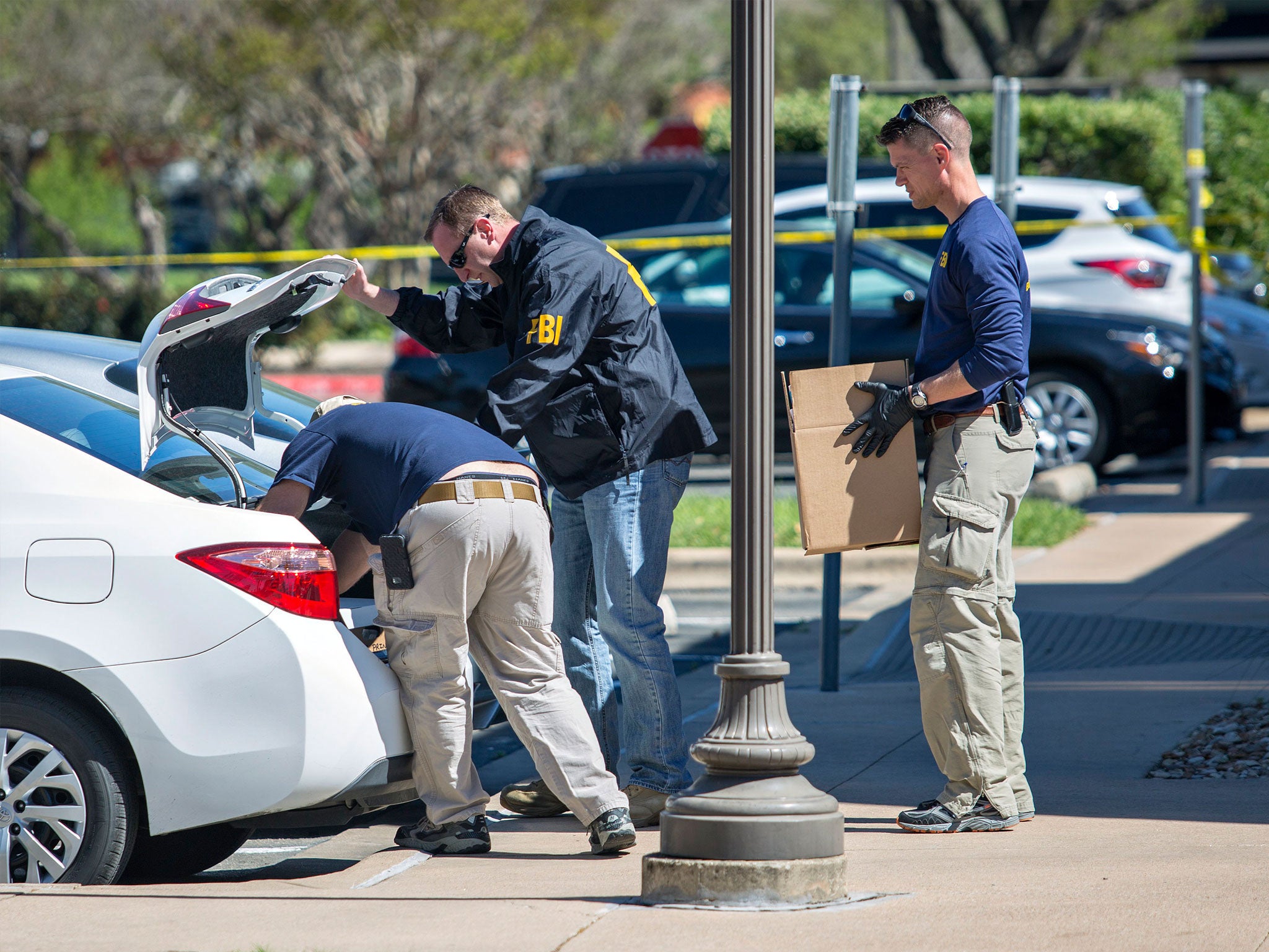 FBI agents are seen carrying items out in paper bags and boxes at a FedEx shop in Austin, Texas