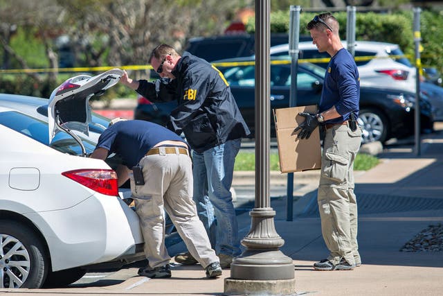 FBI agents are seen carrying items out in paper bags and boxes at a FedEx shop in Austin, Texas