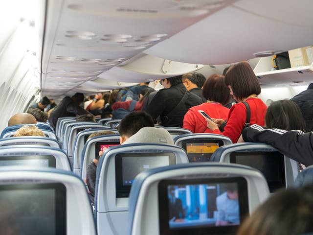 People are standing and sitting in an airplane.