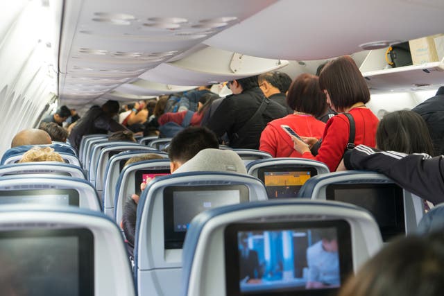 People are standing and sitting in an airplane.