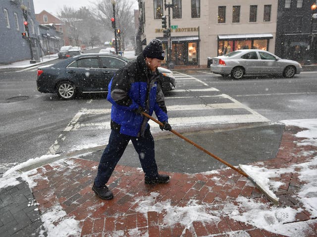 A worker shovels a sidewalk during the latest storm to hit the US east coast, in Washington, DC