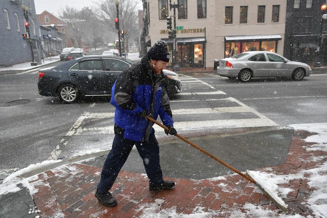 A worker shovels a sidewalk during the latest storm to hit the US east coast, in Washington, DC