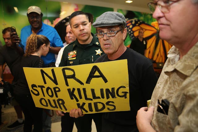 Protesters hold a sign denouncing the NRA and its influence on America's gun policies