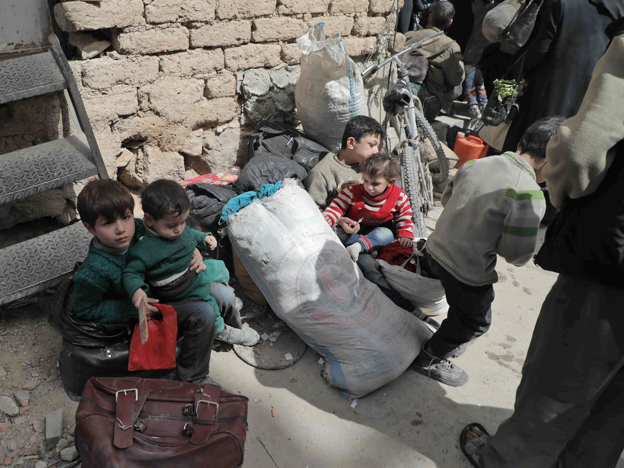 Syrian civilians and children wait for their evacuation by the Syrian Red Crescent