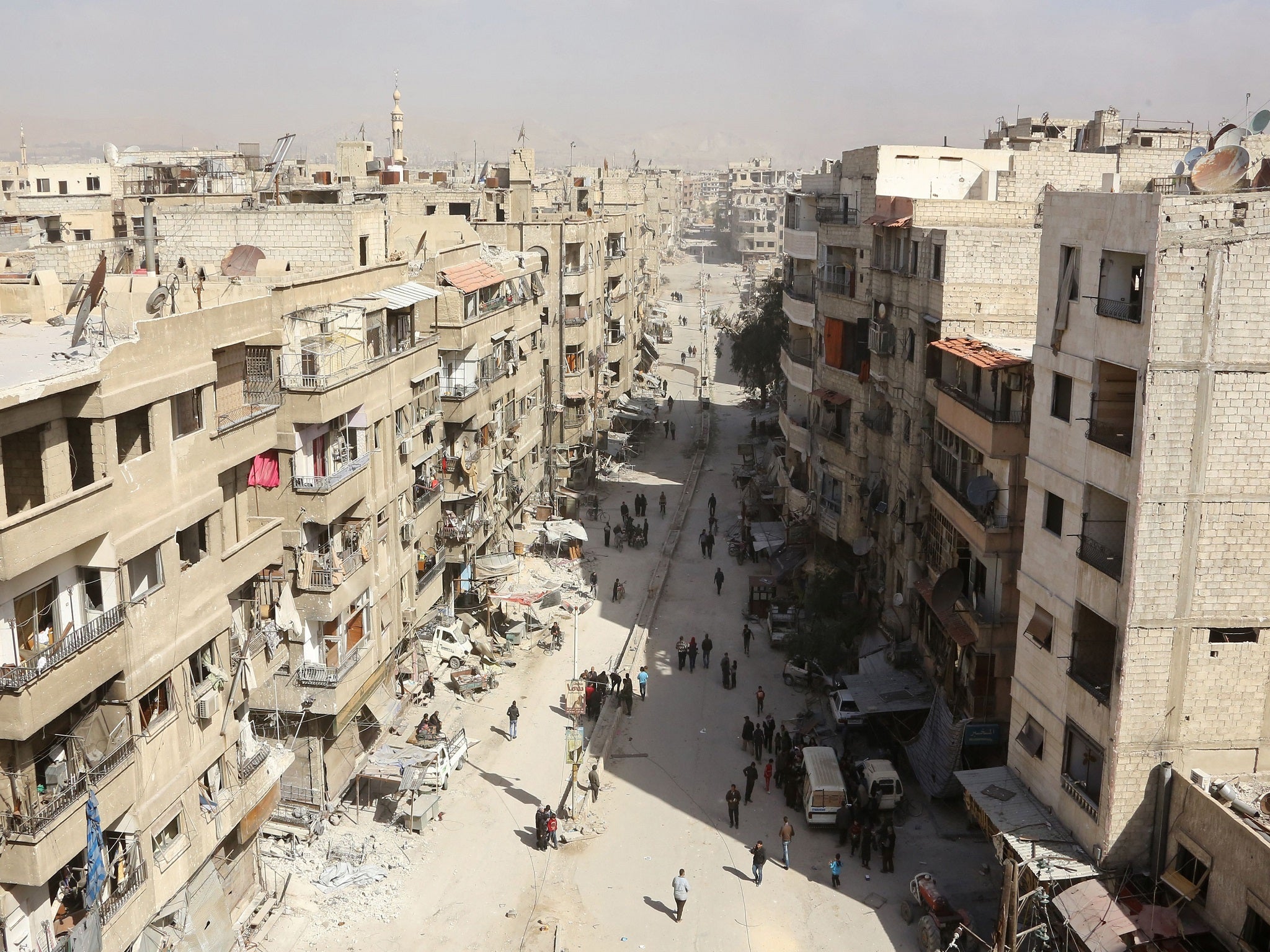 Syrian people walk down a street past destroyed buildings as civilians and rebels prepare to evacuate the town of Ain Tarma in the eastern Ghouta region near Damascus, on March 25, 2018