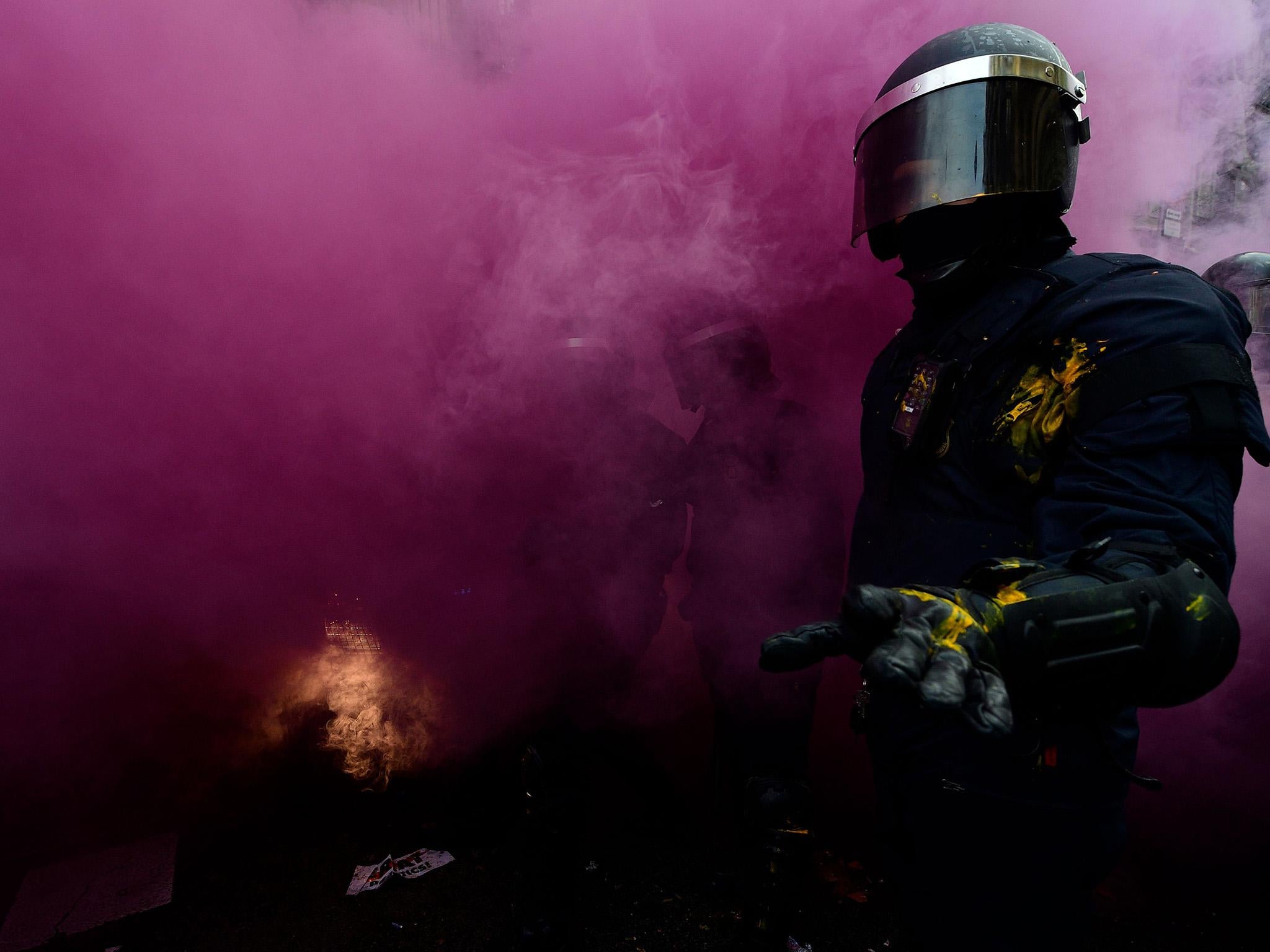 A riot police officer gestures after a smoke bomb was thrown during scuffles between protesters and police blocking the road leading to the central government offices during a demonstration in Barcelona