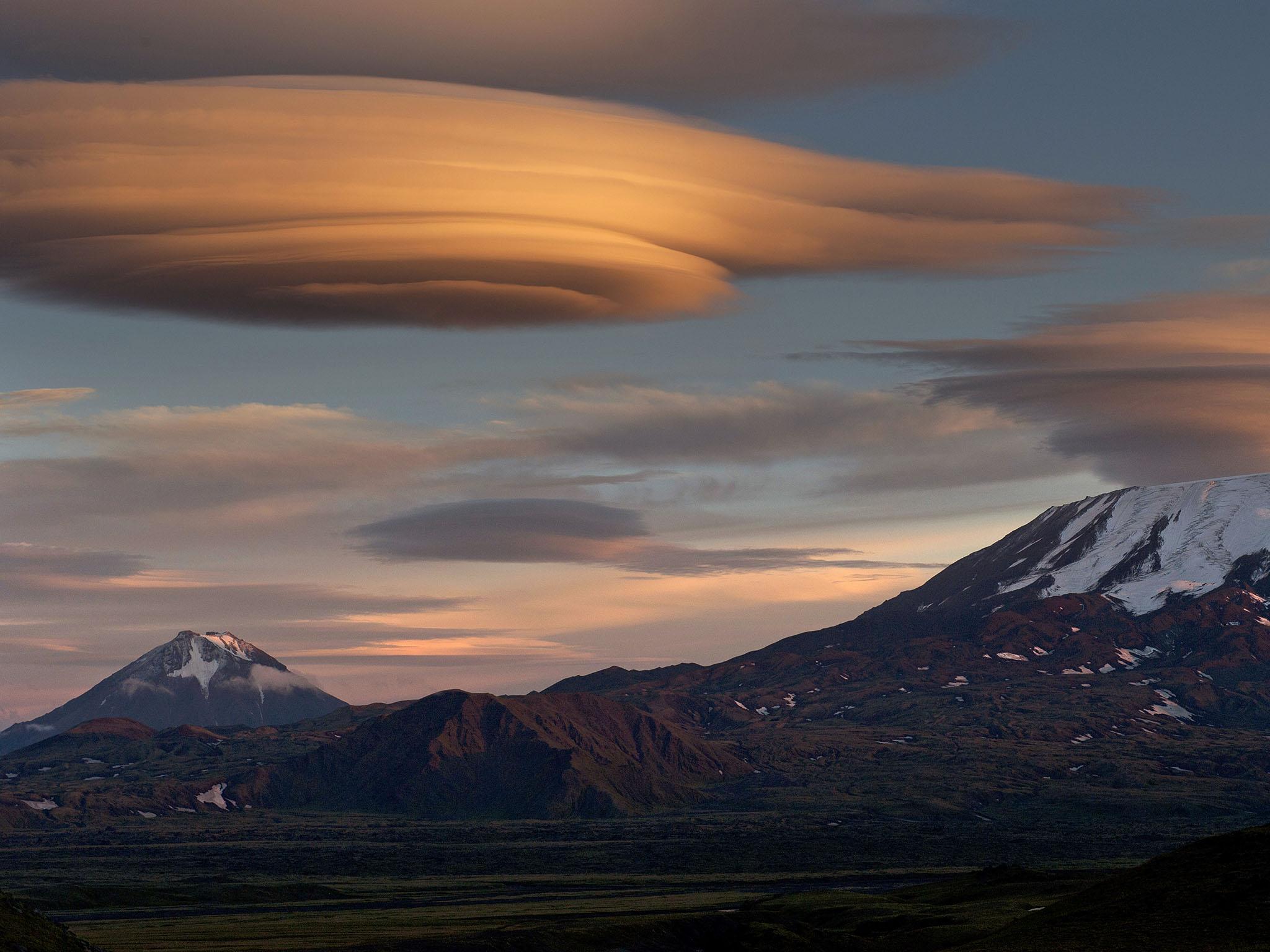 Lenticular clouds form over mountains