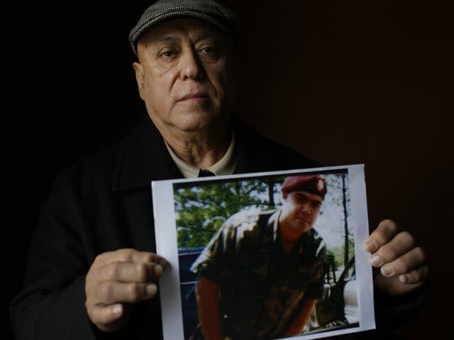 Miguel Perez poses as he holds a photo of his son Miguel Perez Jr., an Army veteran who was just deported after serving seven years in prison on a drug charge.