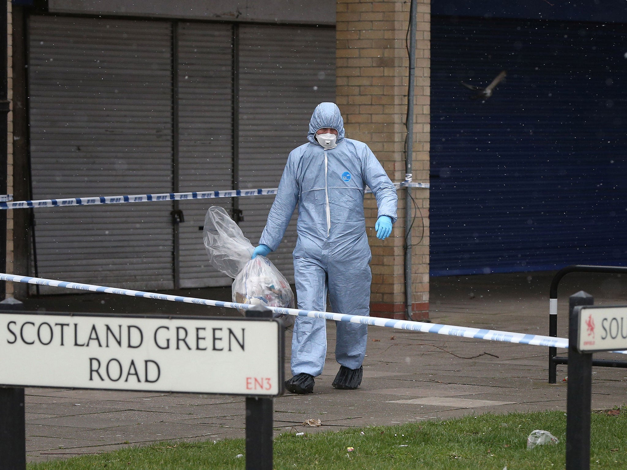 Police at the scene in Enfield, north London where a man died after being found shot and stabbed in the street on 17 March