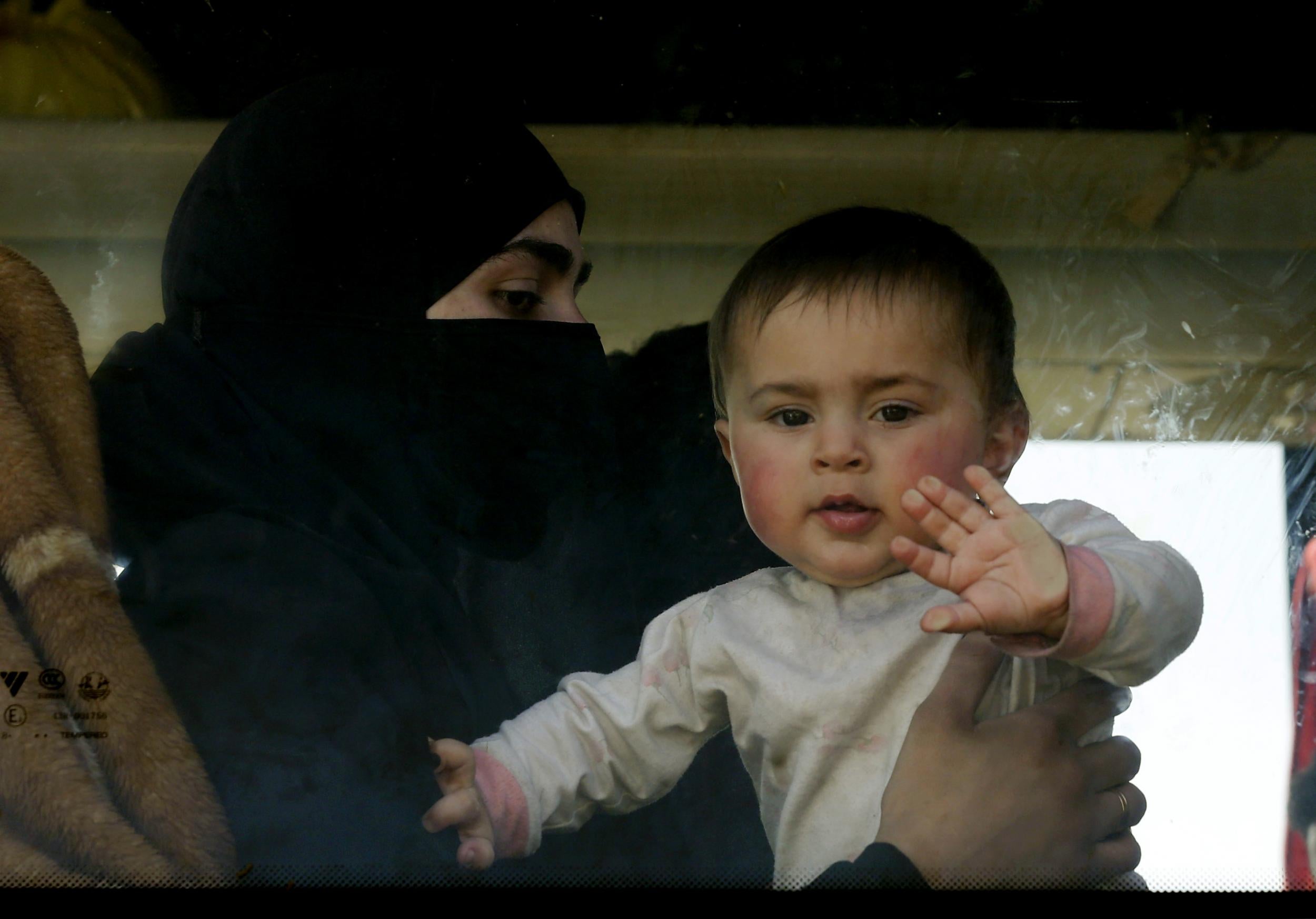A baby waves at the window of a bus as civilians and rebel fighters evacuated from eastern Ghouta arrive in a government-held area at the entrance of Harasta on the outskirts of the capital Damascus on 26 March 2018