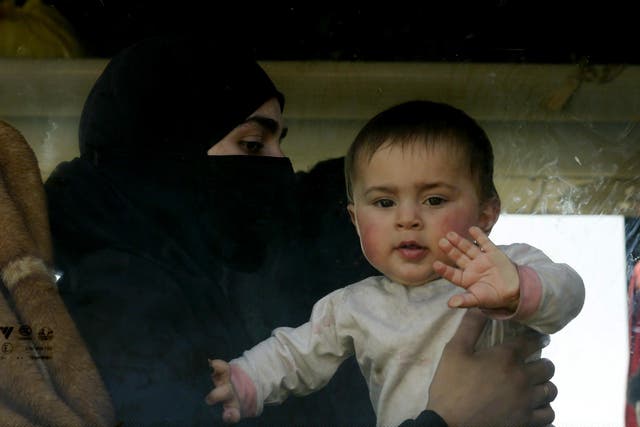 A baby waves at the window of a bus as civilians and rebel fighters evacuated from eastern Ghouta arrive in a government-held area at the entrance of Harasta on the outskirts of the capital Damascus on 26 March 2018