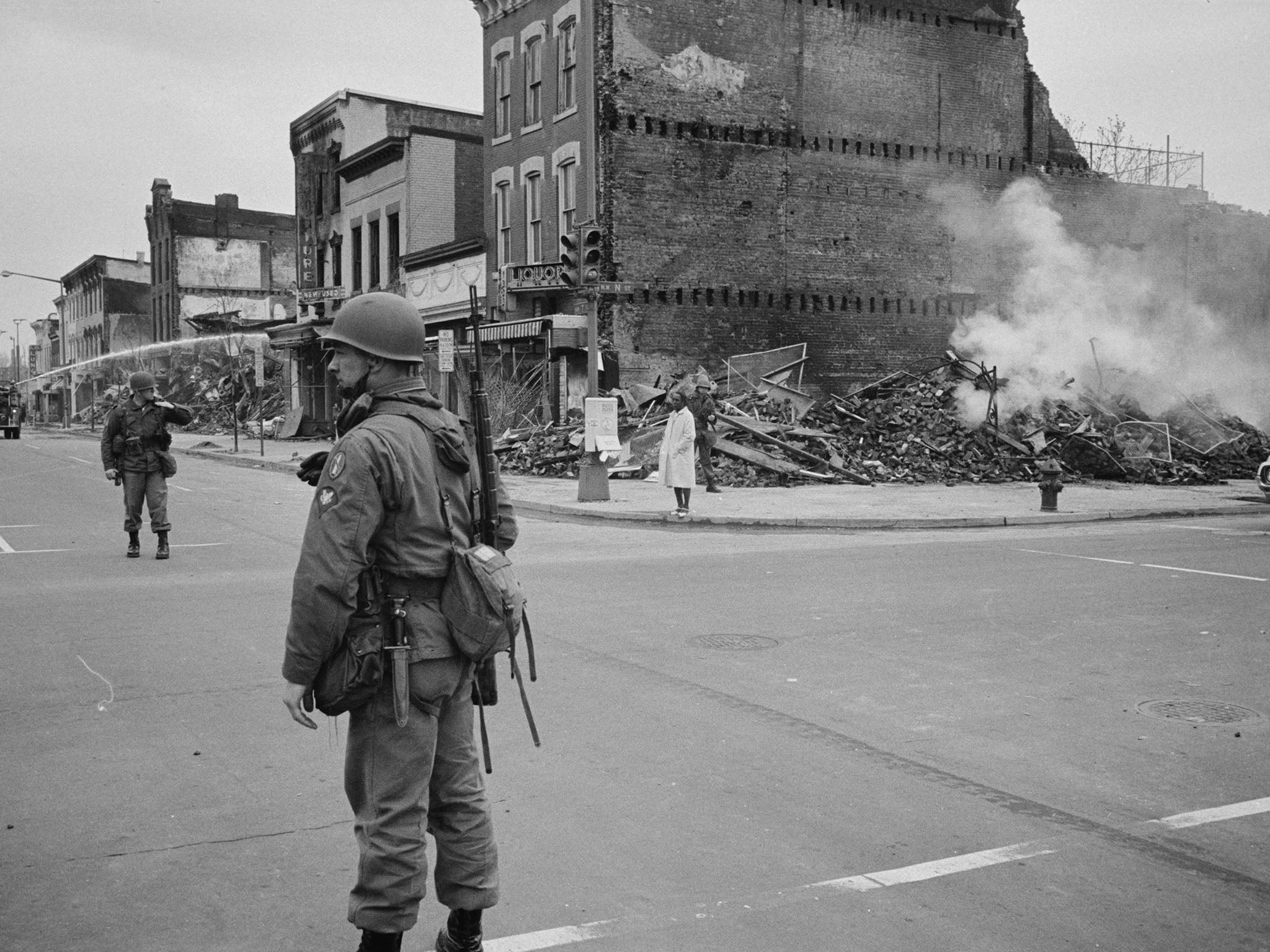 Soldiers stand guard in a Washington street with the ruins of buildings that were destroyed during the riots (Rex)