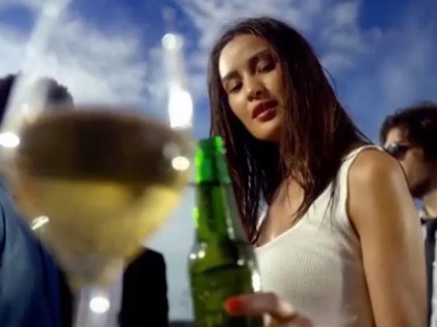 A Heineken ad shows a bartender sliding a bottle of beer past a number of black people before it reaches a light-skinned woman