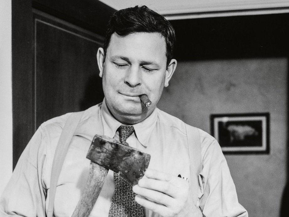 A cigar-chomping detective examines the murder weapon, 1940
