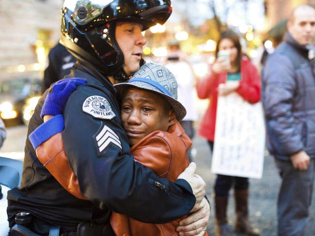 Portland police Sergeant Bret Barnum, left, and Devonte Hart, 12, hug at a rally in Portland, Oregon, where people had gathered in support of the protests in Ferguson