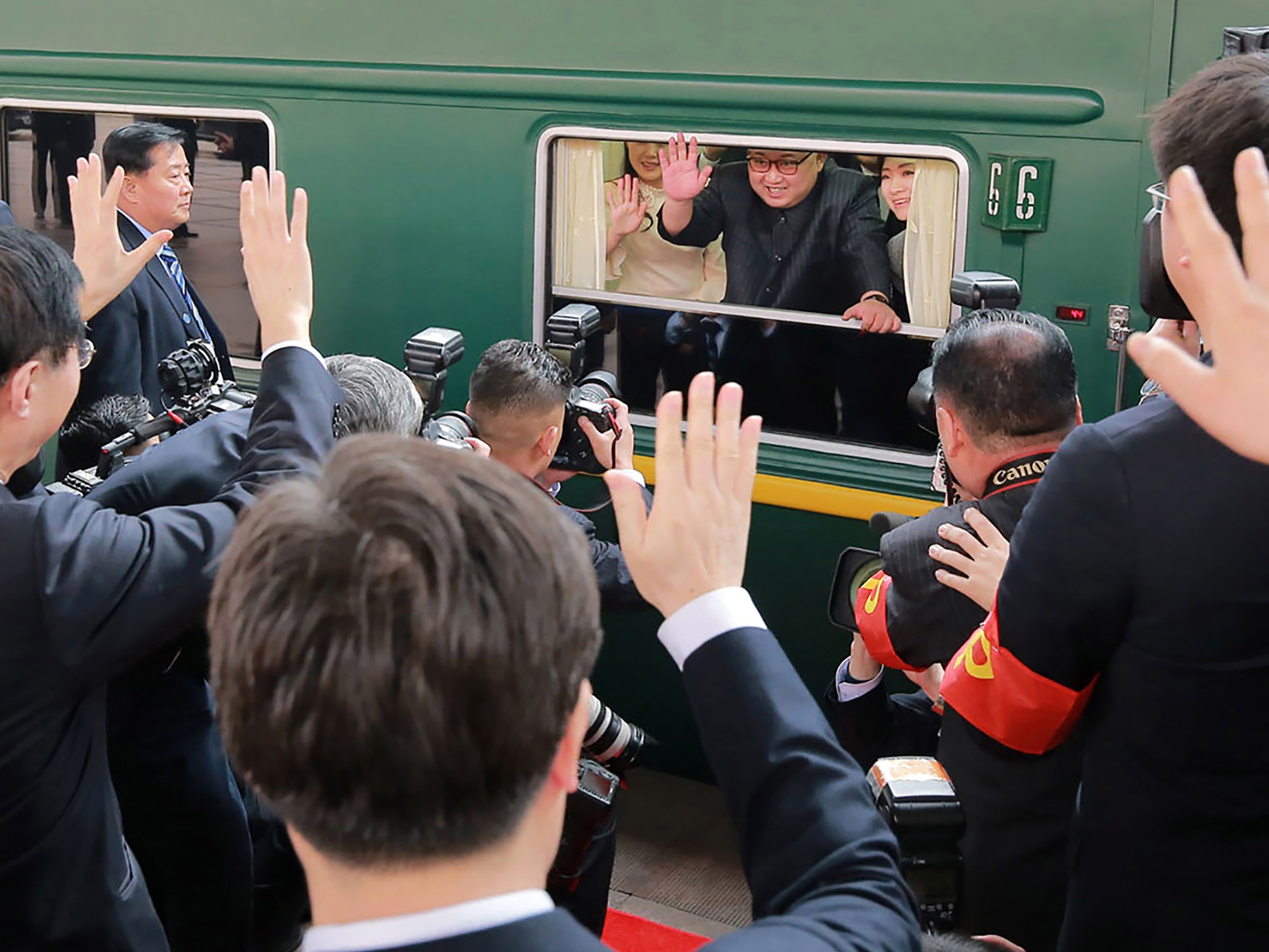Kim Jong-un waves from inside his train as he prepares to depart from Beijing, in this photo released by KCNA