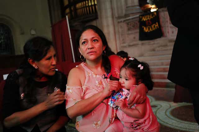 Aura Hernandez, a 37-year-old woman from Guatemala taking sanctuary in a Manhattan church, holds her 15-month-old daughter during a vigil and procession