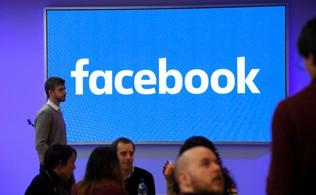 People stand in front of a logo at Facebook's headquarters in London